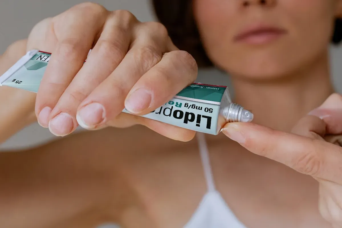 Eine weibliche Person drückt Creme aus einer Tube Lidoproct auf ihren Zeigefinger