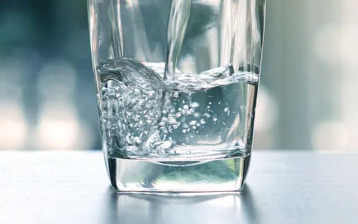 Wasser wird in ein Glas gekippt