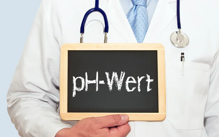 Ein medizinisches Personal hält eine Kreidetafel mit der Aufschrift "pH-Wert" in der Hand