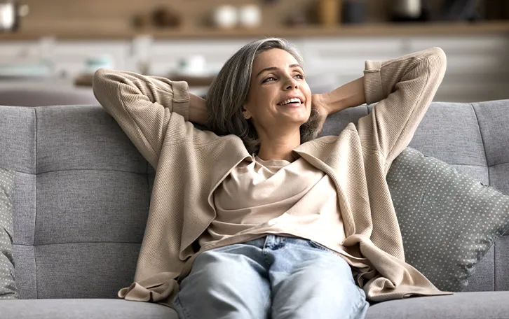 Eine auf einer Couch entspannt sitzende weibliche Person