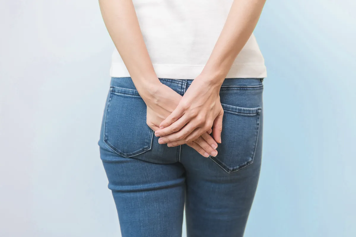 Eine Person hält sich beide Hände in der Höhe Ihrer Jeanshosentaschen auf das Gesäß